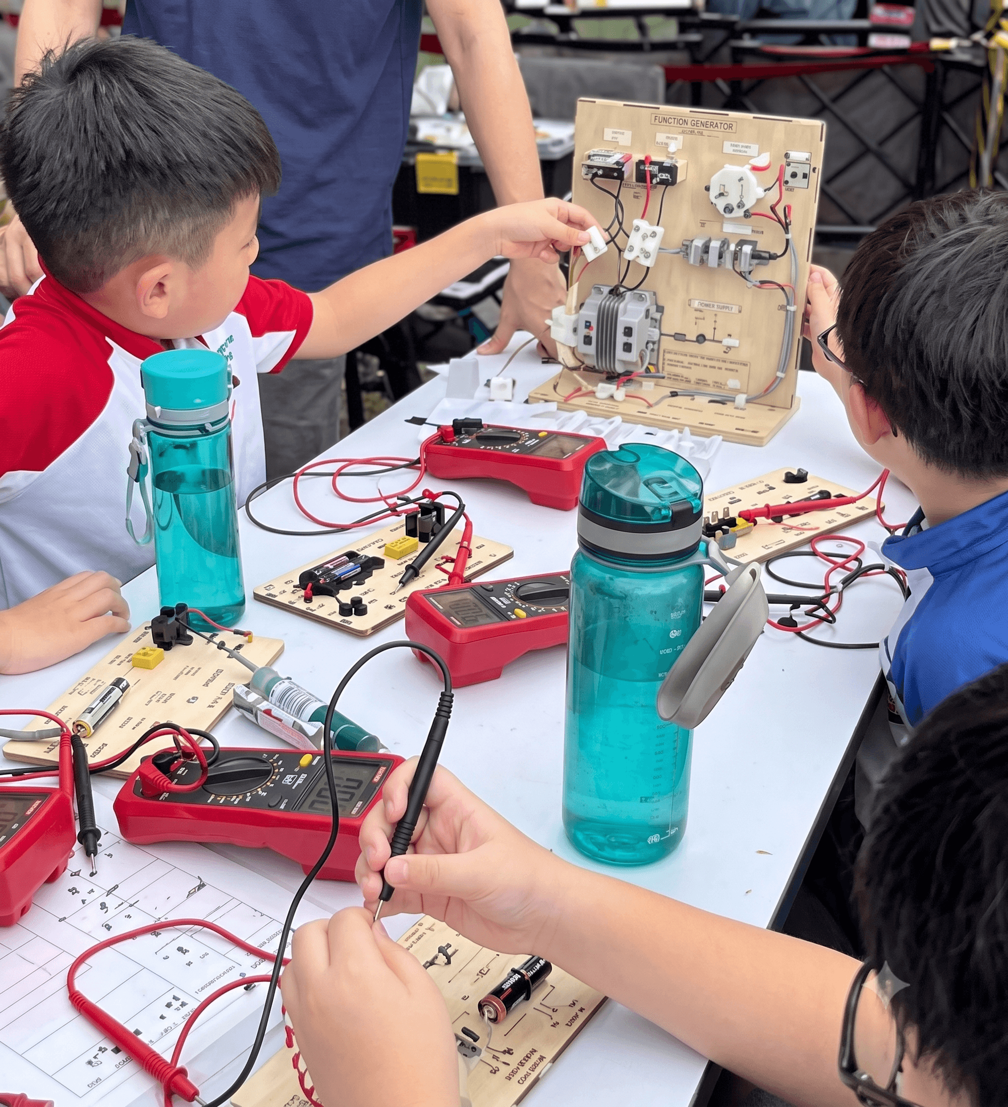 Mindset over mastery: Young learners using interactive training kits to test diagnostic hypotheses during a Repair@School community booth activity.