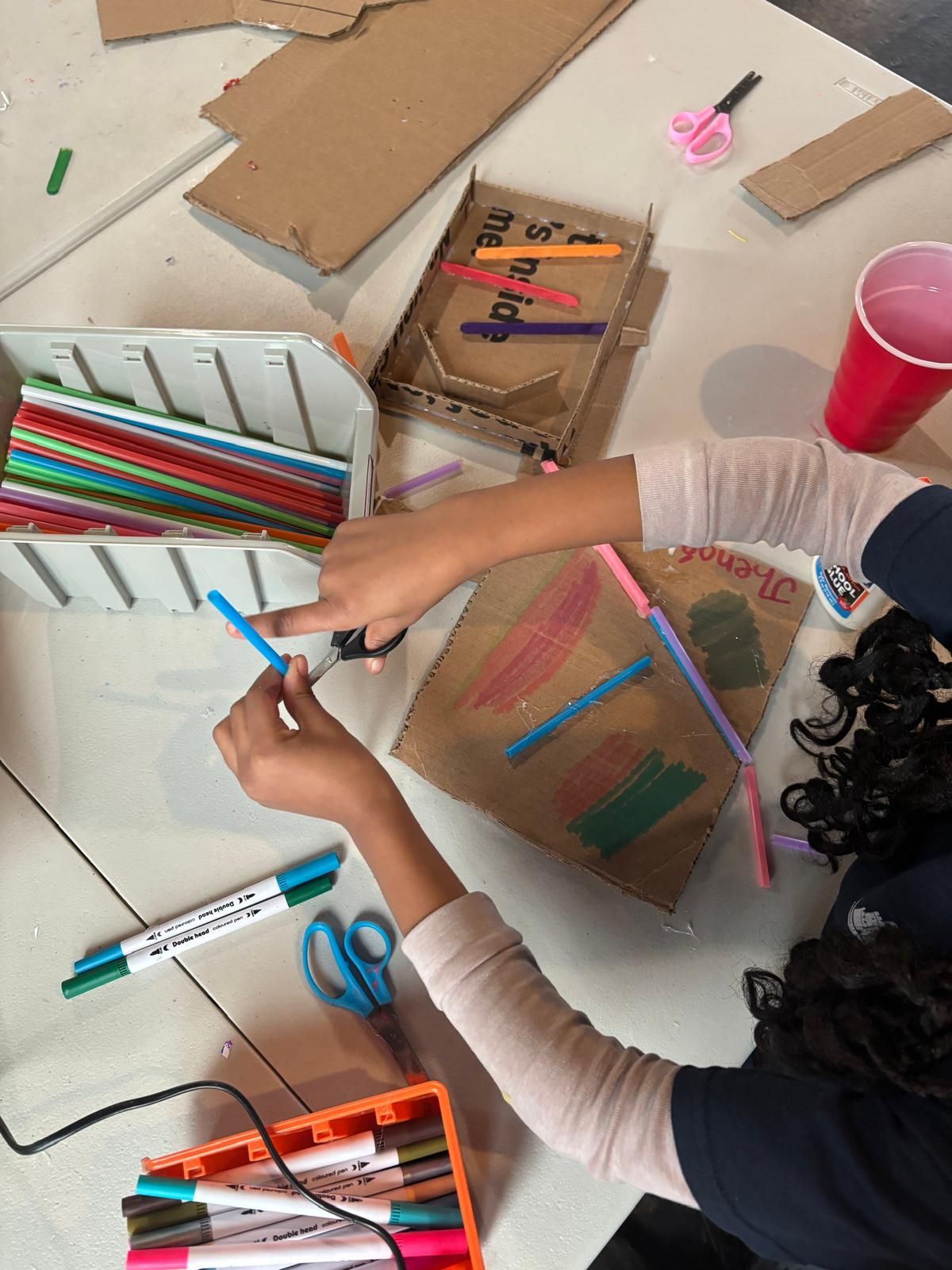 Students building with simple materials (paper, cardboard, markers)